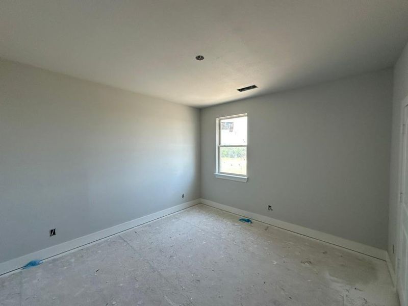 Room featuring a window with white trim, light gray painted walls, and white baseboards