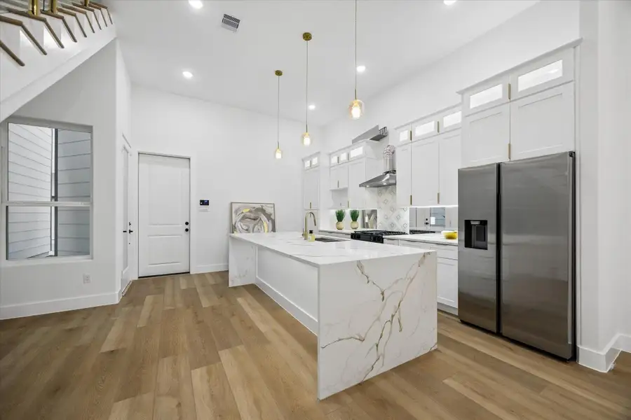 This modern kitchen features sleek white cabinetry, a spacious island with a marble finish, and stainless steel appliances. The open layout and ample lighting create a bright, inviting atmosphere, perfect for cooking and entertaining. This modern kitchen features sleek white cabinetry, a spacious island with a marble finish, and stainless steel appliances. The open layout and ample lighting create a bright, inviting atmosphere, perfect for cooking and entertaining.
