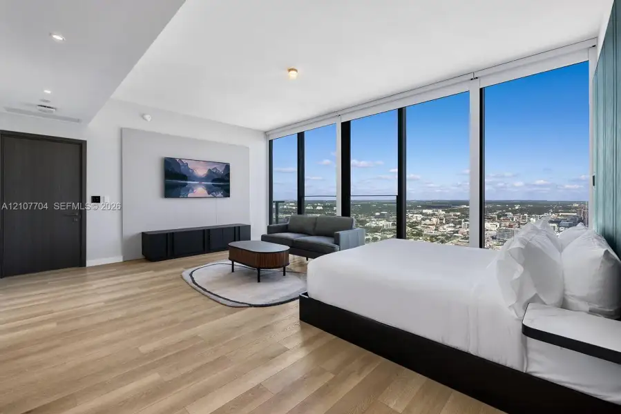 Floor-to-ceiling windows, wood-finish flooring, recessed lighting, and wall-mounted accent paneling