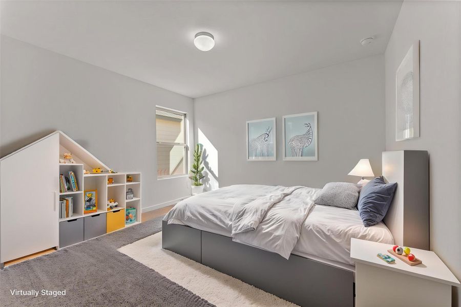 A well-lit bedroom features hardwood flooring and abundant natural light streaming through the window.