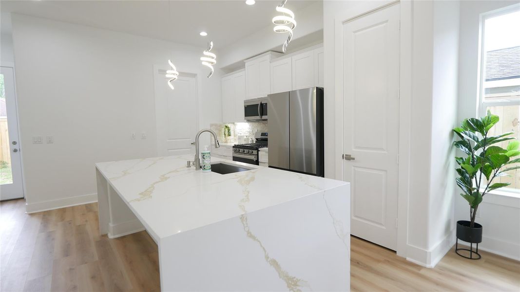 This modern kitchen features a spacious luxury island with sleek countertops, stainless steel appliances, and stylish pendant lighting. The space is bright with natural light, enhanced by light wood flooring and white cabinetry. This modern kitchen features a spacious luxury island with sleek countertops, stainless steel appliances, and stylish pendant lighting. The space is bright with natural light, enhanced by light wood flooring and white cabinetry.