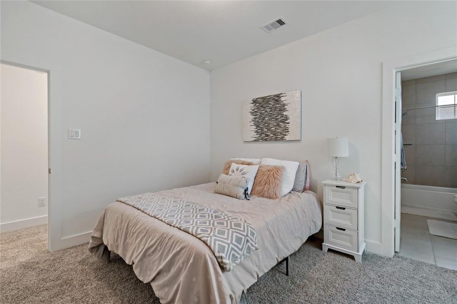 Charming bedroom with plush carpeting and soft neutral tones, featuring a cozy bed and convenient ensuite bathroom access. Charming bedroom with plush carpeting and soft neutral tones, featuring a cozy bed and convenient ensuite bathroom access.