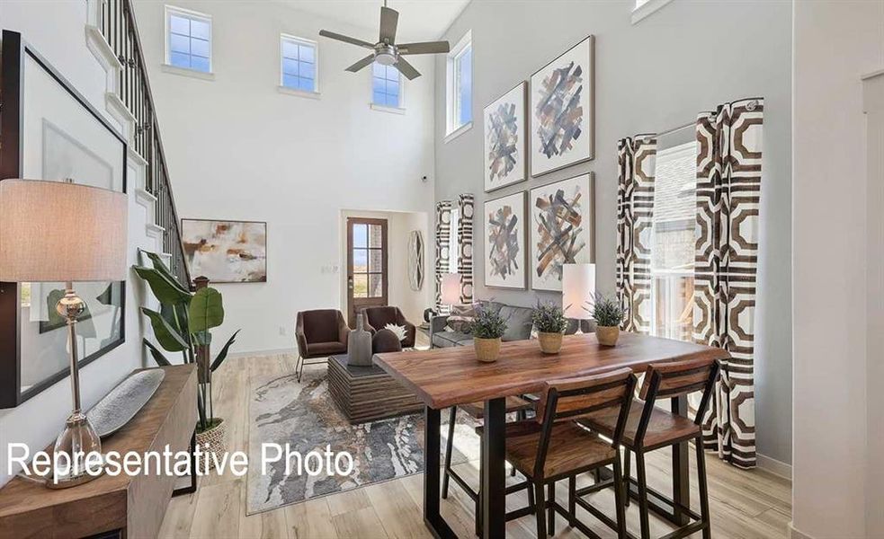 Dining space with a high ceiling, light wood-type flooring, and ceiling fan