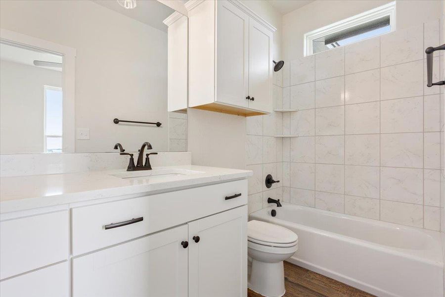A well-lit bathroom features a vanity with sleek fixtures and a bathtub with tiled surround.