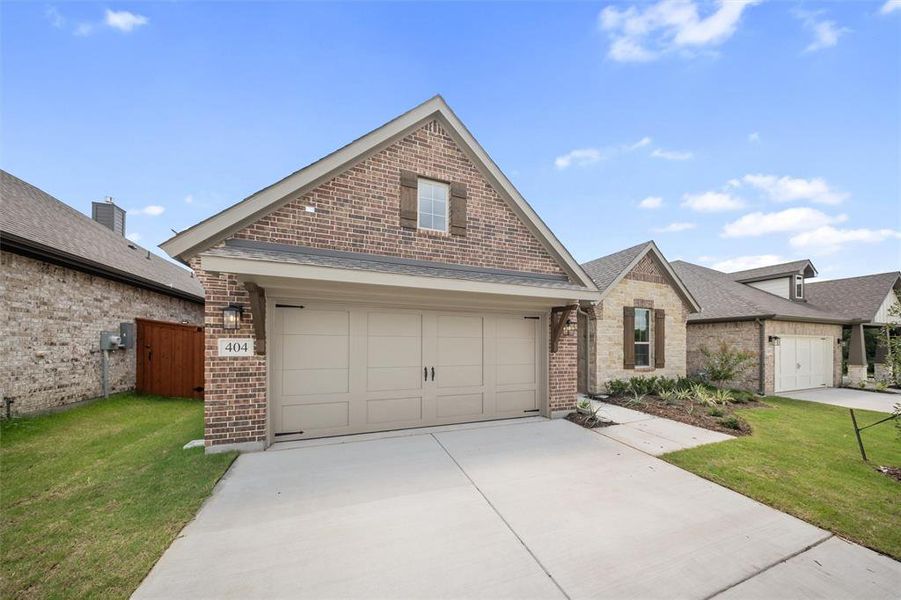 View of front of property with a garage, brick siding, and roof with shingles