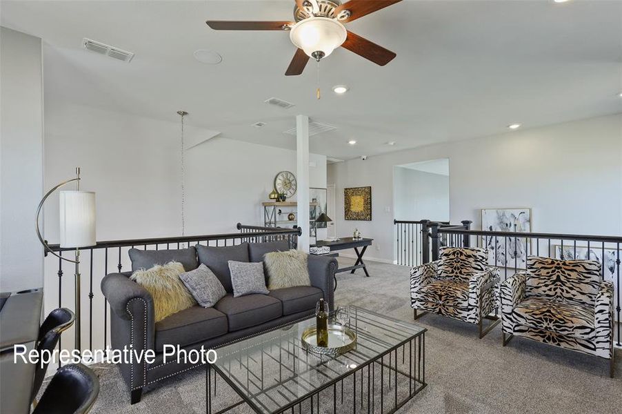 Spacious carpeted open-concept bonus room featuring a ceiling fan with light fixture, recessed lighting, and a black wrought iron railing system