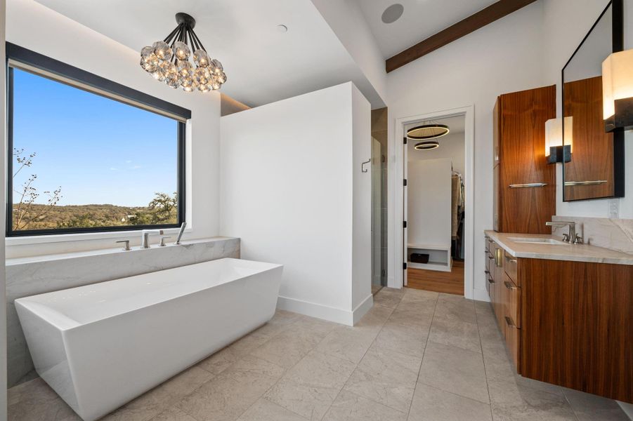 Full bath featuring a stall shower, a notable chandelier, vanity, lofted ceiling, and a freestanding bath Full bath featuring a stall shower, a notable chandelier, vanity, lofted ceiling, and a freestanding bath