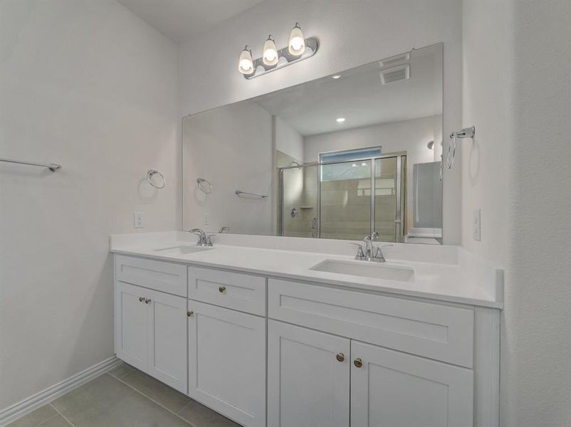 Bathroom featuring tile patterned flooring, vanity, and an enclosed shower