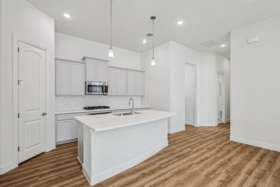 Kitchen featuring hardwood / wood-style floors, a kitchen island with sink, and sink