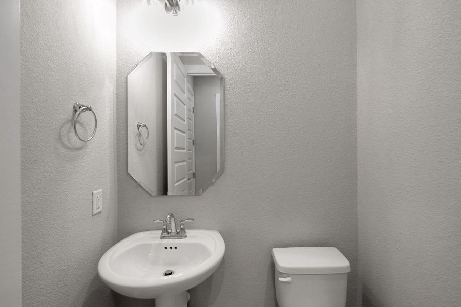 Bathroom featuring toilet and a textured wall Bathroom featuring toilet and a textured wall