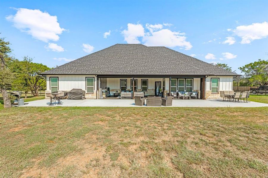 Rear view of property featuring a patio area, outdoor lounge area, a shingled roof, and a yard Rear view of property featuring a patio area, outdoor lounge area, a shingled roof, and a yard