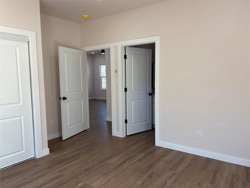 Unfurnished primary bedroom with baseboards and dark wood-style floors