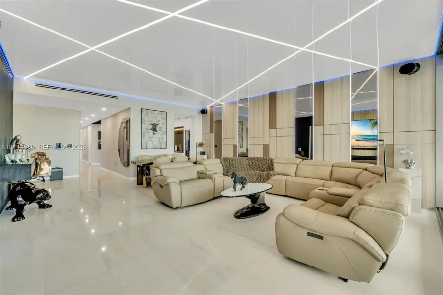 High-gloss ceiling featuring integrated linear LED lighting, polished stone-finish flooring, and vertical wood-paneled accent wall with inset mirrored panels High-gloss ceiling featuring integrated linear LED lighting, polished stone-finish flooring, and vertical wood-paneled accent wall with inset mirrored panels