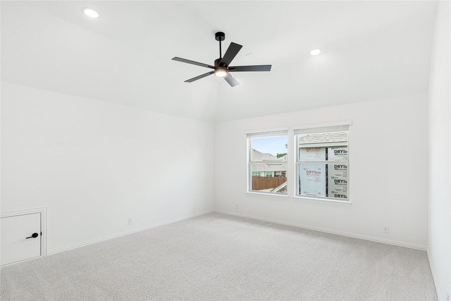 Empty bedroom with white walls, carpet flooring, ceiling fan, and a double window