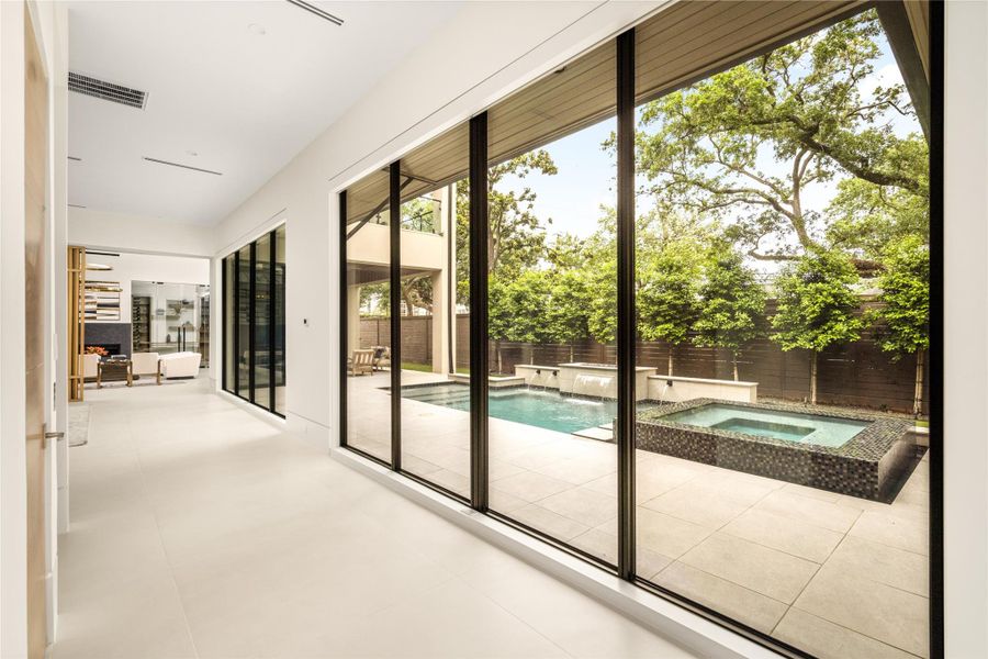 Walls of glass create a seamless connection to the outdoor living spaces, overlooking the pool and landscaped grounds.