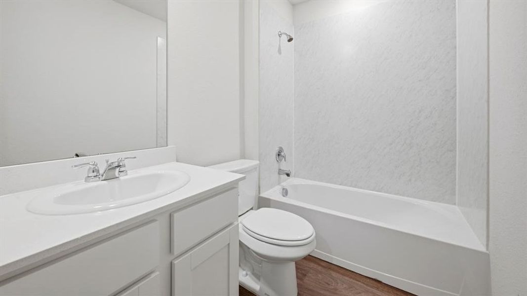 Bathroom featuring vanity, shower / washtub combination, and dark wood-style floors Bathroom featuring vanity, shower / washtub combination, and dark wood-style floors