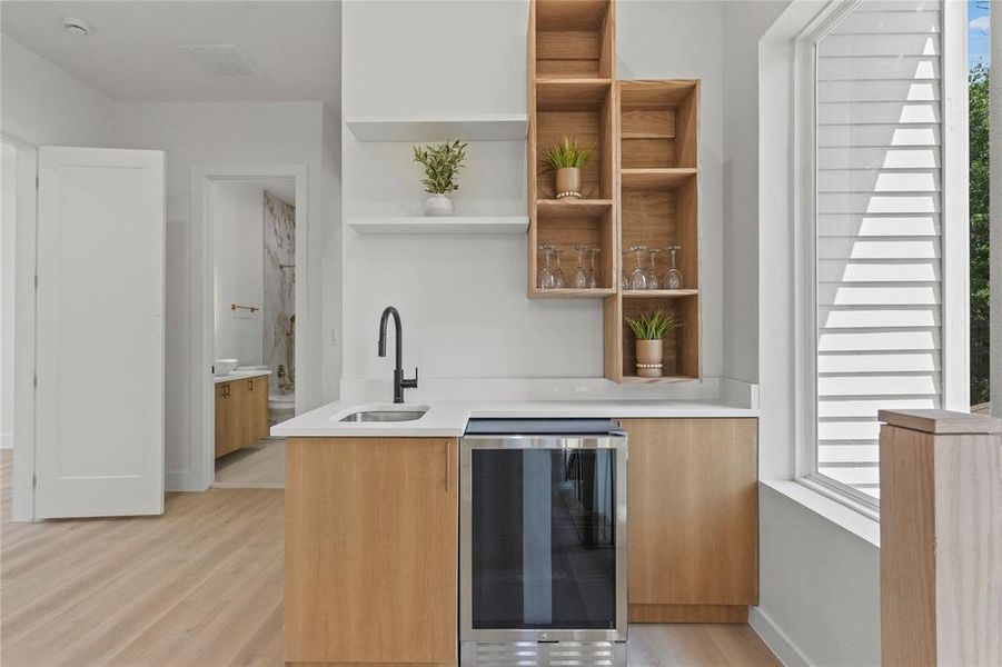 Wet-Bar with sink, light wood-type flooring, and beverage cooler