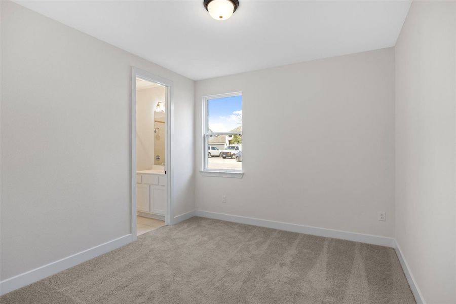 Unfurnished bedroom featuring light carpet and ensuite bath Unfurnished bedroom featuring light carpet and ensuite bath