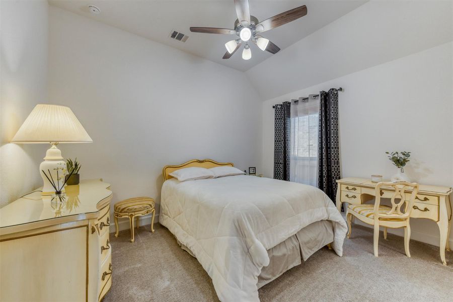 Bedroom with lofted ceiling, light colored carpet, and a ceiling fan