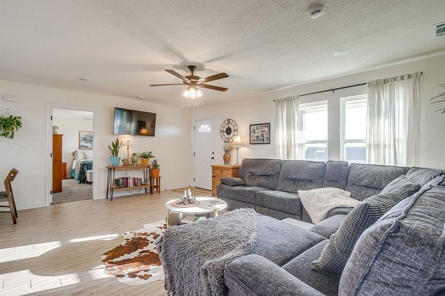 Living room with wood-style tile floors, ceiling fan, and natural light. Living room with wood-style tile floors, ceiling fan, and natural light.