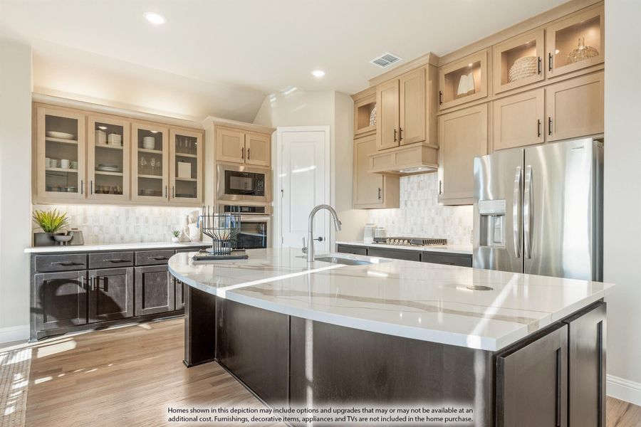 Kitchen with curved island, white countertops, two-tone cabinets, and stainless steel appliances on hardwood floors Kitchen with curved island, white countertops, two-tone cabinets, and stainless steel appliances on hardwood floors
