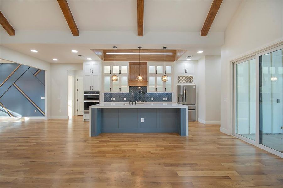 Kitchen with white cabinetry, recessed lighting, tasteful backsplash, hanging light fixtures, and a large island with sink