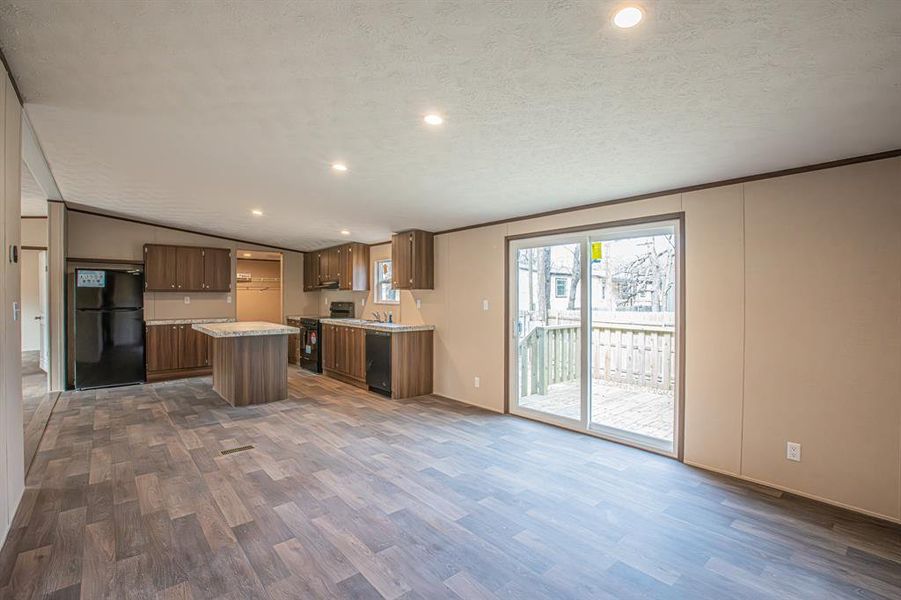 Kitchen with a center island, dark wood-type flooring, black appliances, vaulted ceiling, and a textured ceiling Kitchen with a center island, dark wood-type flooring, black appliances, vaulted ceiling, and a textured ceiling