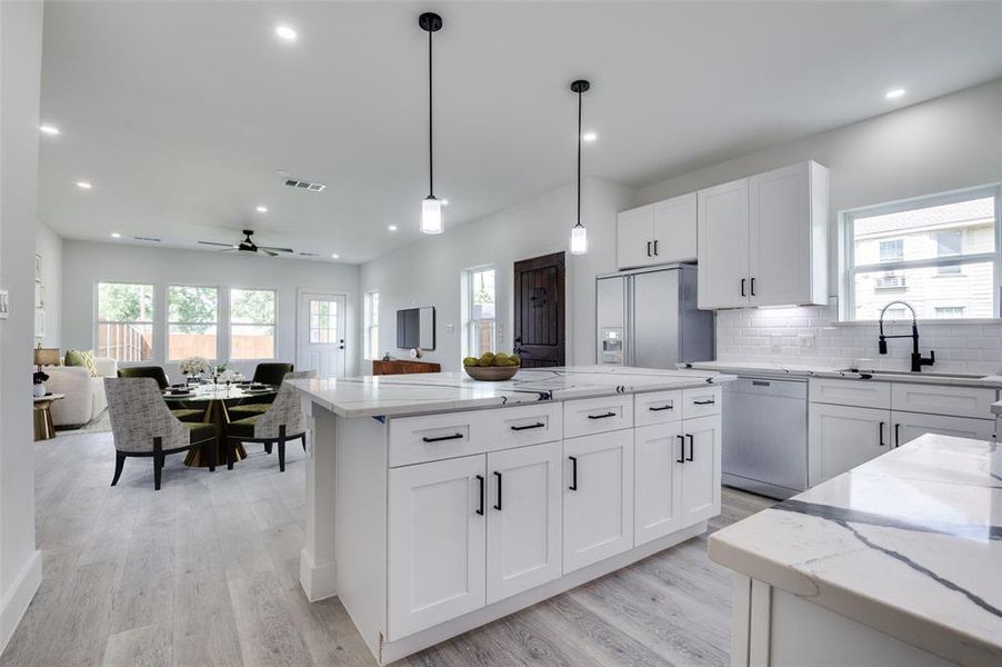 Kitchen with refrigerator with ice dispenser, light wood-style floors, a ceiling fan, dishwasher, and healthy amount of natural light Kitchen with refrigerator with ice dispenser, light wood-style floors, a ceiling fan, dishwasher, and healthy amount of natural light