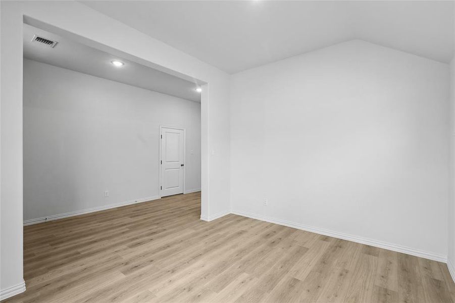 Unfurnished room featuring light wood-style floors, lofted ceiling, and recessed lighting