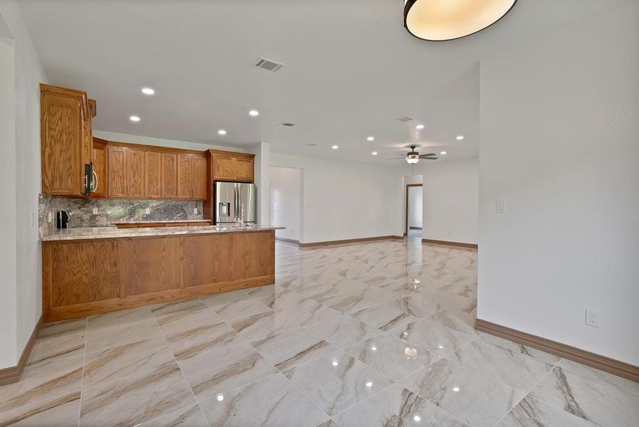 Kitchen featuring a peninsula, recessed lighting, backsplash, stainless steel fridge with ice dispenser, and open floor plan