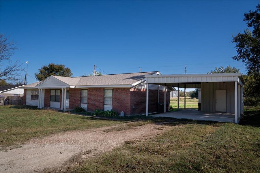 View of front of home featuring a front lawn, dirt driveway, brick siding, and board and batten siding