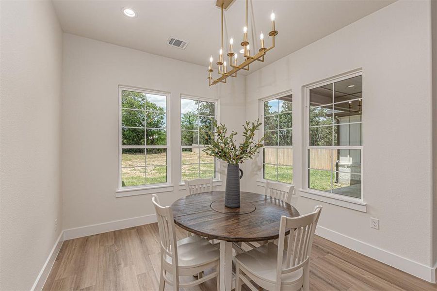 Dining space featuring a linear chandelier with a gold-tone finish, recessed lighting, and wood-finish flooring