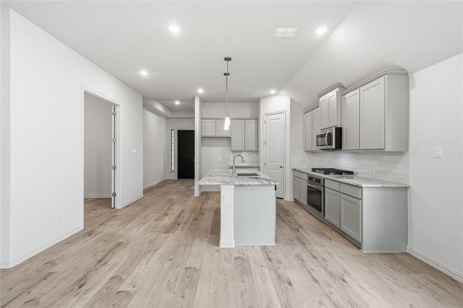 Contemporary kitchen with light wood-finish flooring, light gray cabinetry, and white subway tile backsplash Contemporary kitchen with light wood-finish flooring, light gray cabinetry, and white subway tile backsplash