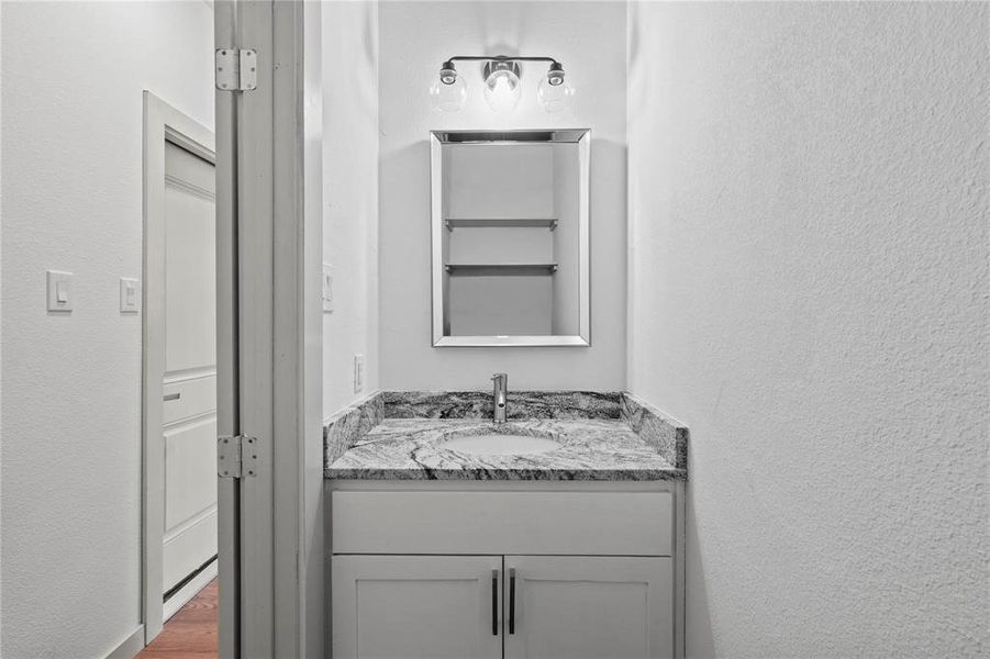 Bathroom featuring a textured wall and vanity