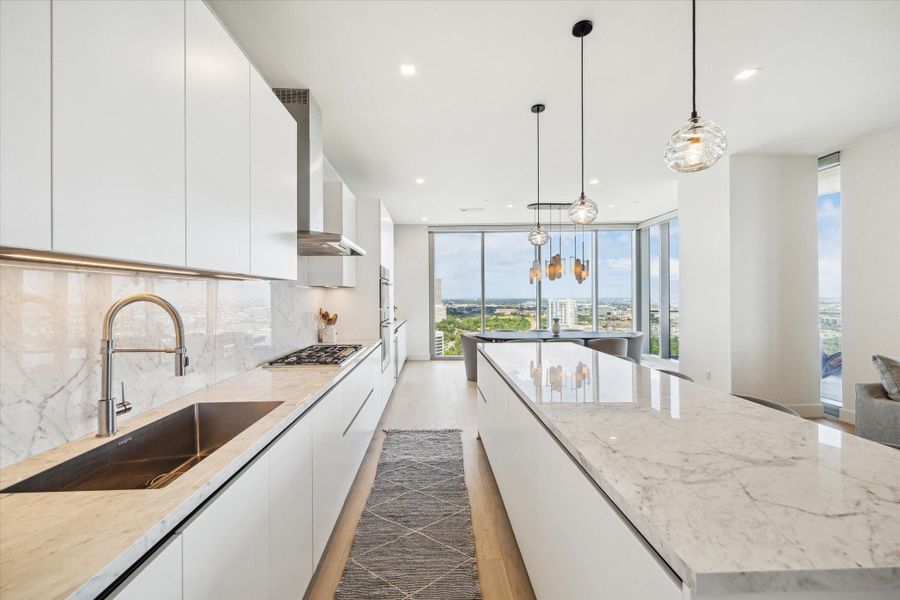 Pendant lighting handcrafted by Siemon and Salazar accent the porcelain countertops in the large kitchen.
