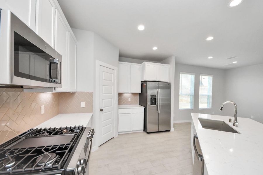 Discover another perspective of this stunning kitchen, generously appointed with an abundance of counter space. Sample photo of completed home with similar floor plan. Actual colors and selections may vary. Discover another perspective of this stunning kitchen, generously appointed with an abundance of counter space. Sample photo of completed home with similar floor plan. Actual colors and selections may vary.