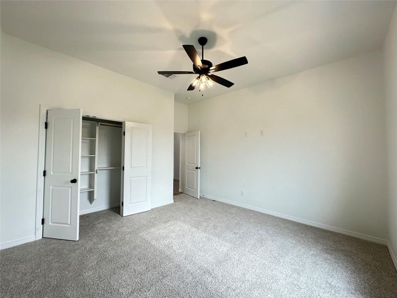 Unfurnished bedroom featuring carpet flooring, a closet, and a ceiling fan
