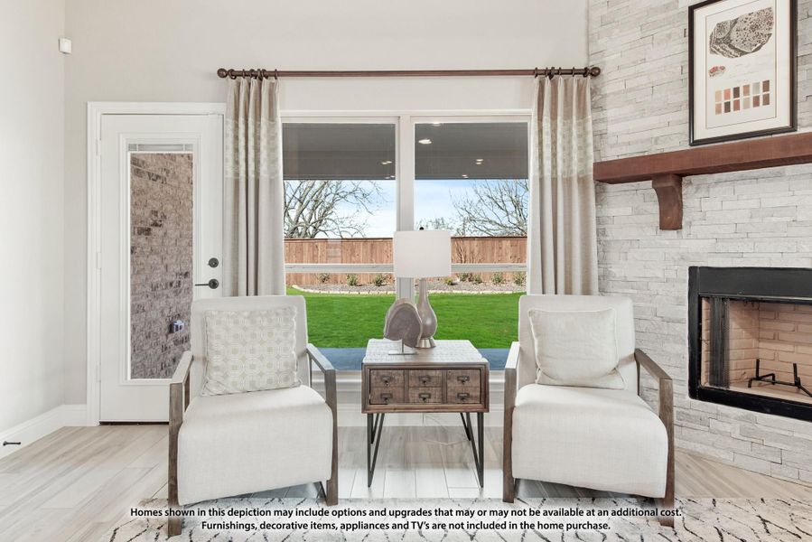 Living room with two white chairs, stone fireplace, and large window overlooking backyard