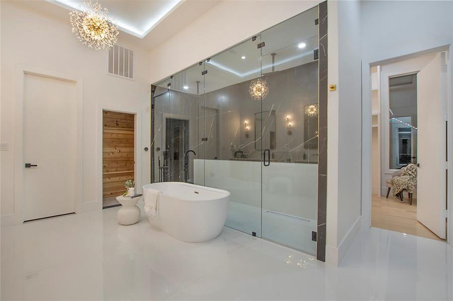 Bathroom featuring tile patterned flooring, a notable chandelier, separate shower and tub, and a tray ceiling