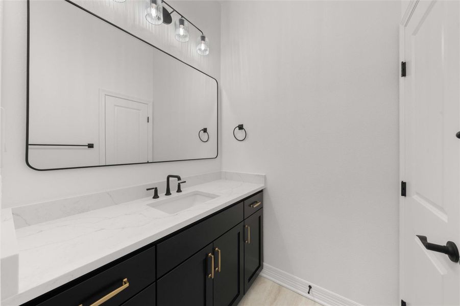A well-lit bathroom features a spacious vanity with sleek black cabinetry and pristine white countertops. A well-lit bathroom features a spacious vanity with sleek black cabinetry and pristine white countertops.