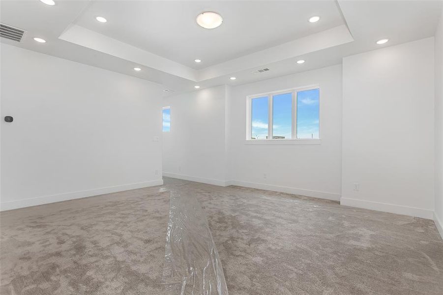 Carpeted empty room featuring a raised ceiling