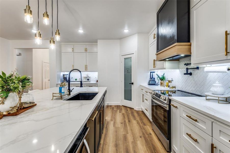 Kitchen with white cabinetry, stainless steel electric stove, light stone counters, decorative light fixtures, and light wood-style floors