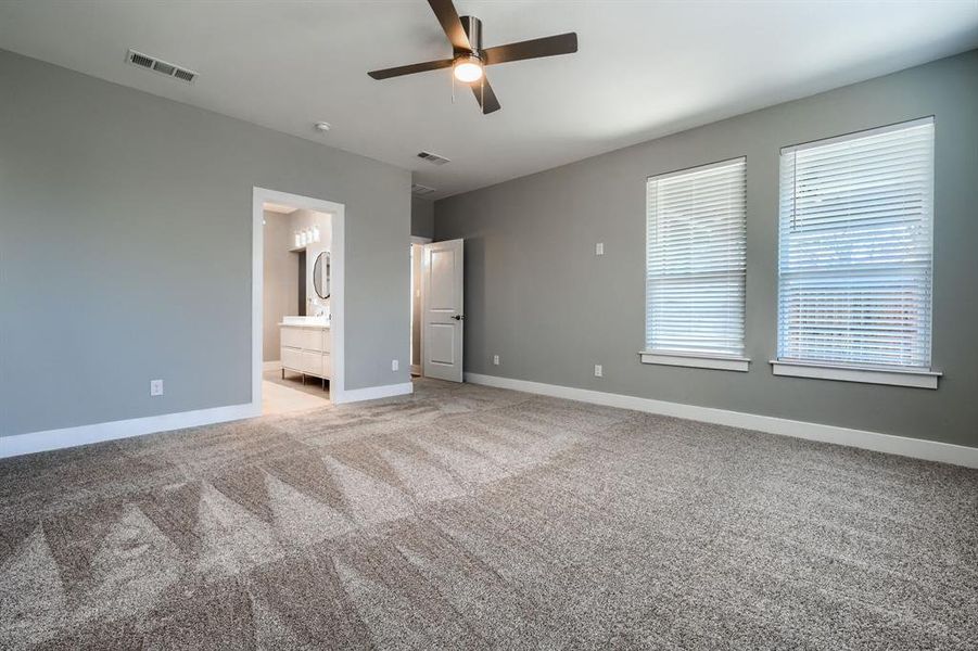 Unfurnished bedroom featuring carpet, ceiling fan, and ensuite bath