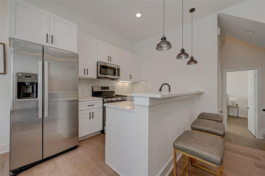This waterfall-edge quartz island is a showstopper featuring an undermount stainless sink, matte black pull-down faucet, and sleek pendant lights above. Clean, modern, and ready to impress.