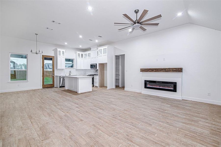 Kitchen with open floor plan, stainless steel appliances, light countertops, backsplash, and white cabinetry Kitchen with open floor plan, stainless steel appliances, light countertops, backsplash, and white cabinetry