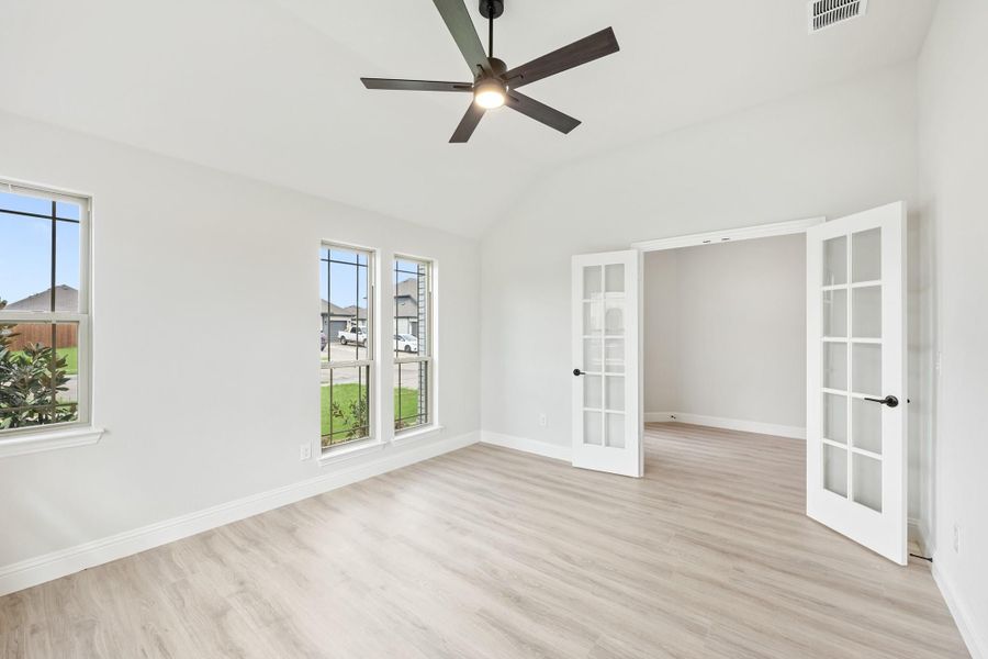 Empty room with light wood floors, ceiling fan, and French doors with glass panels