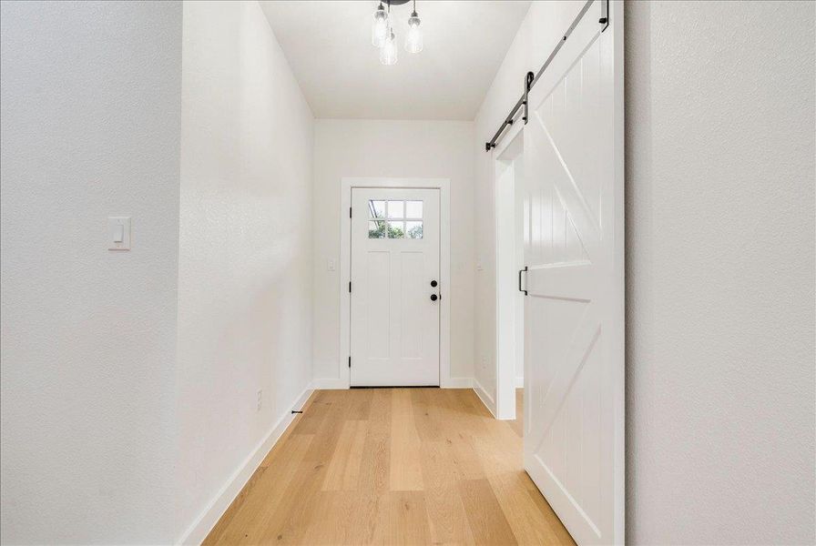 Bright entry hall features durable hardwood flooring and a stylish barn door.