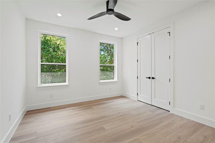 Unfurnished bedroom featuring multiple windows, light wood-style flooring, recessed lighting, and a ceiling fan
