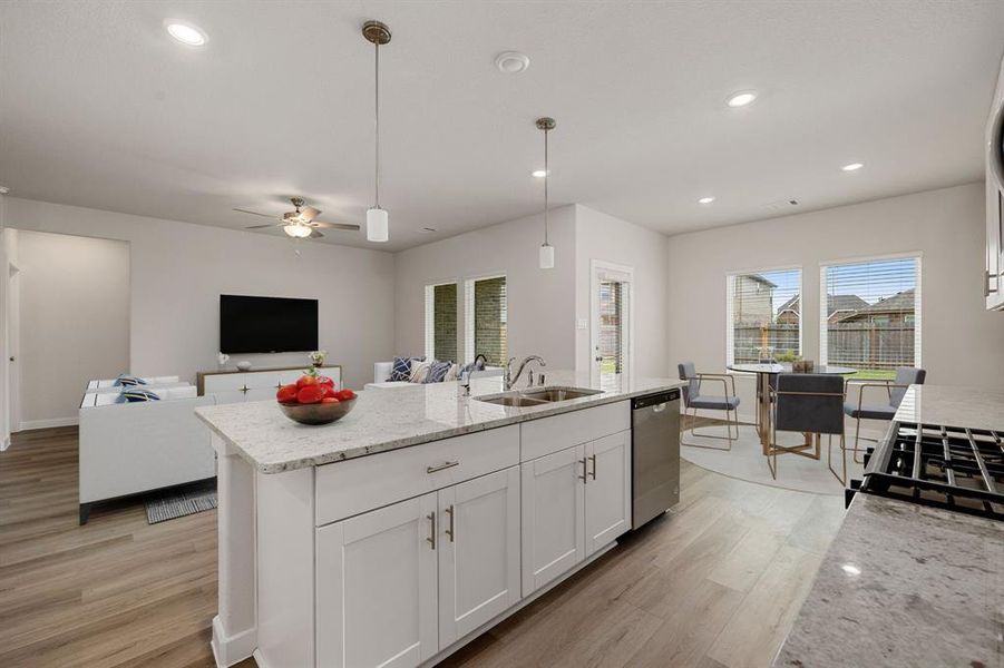 Just look at this amazing and immaculate kitchen! This kitchen conveniently connects to the dining room, and family room for easy entertaining.  It features EVP floors, bright kitchen cabinets that open up this space even more, large island, open floorplan, and ample counter space.