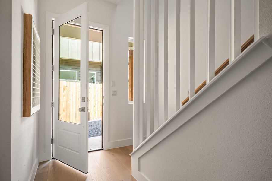 A welcoming entryway with natural light, featuring elegant wood flooring and a contemporary stair railing. A welcoming entryway with natural light, featuring elegant wood flooring and a contemporary stair railing.